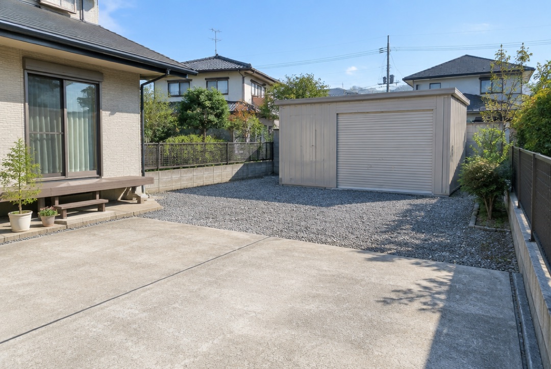 住宅の庭の奥に建てたベージュのスチールガレージ