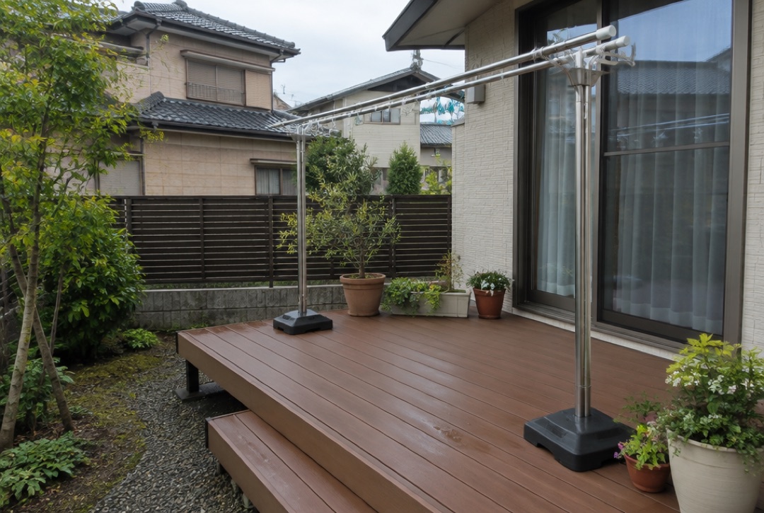 物干しと鉢植えを置いたブラウンの人工木ウッドデッキがある住宅の裏庭