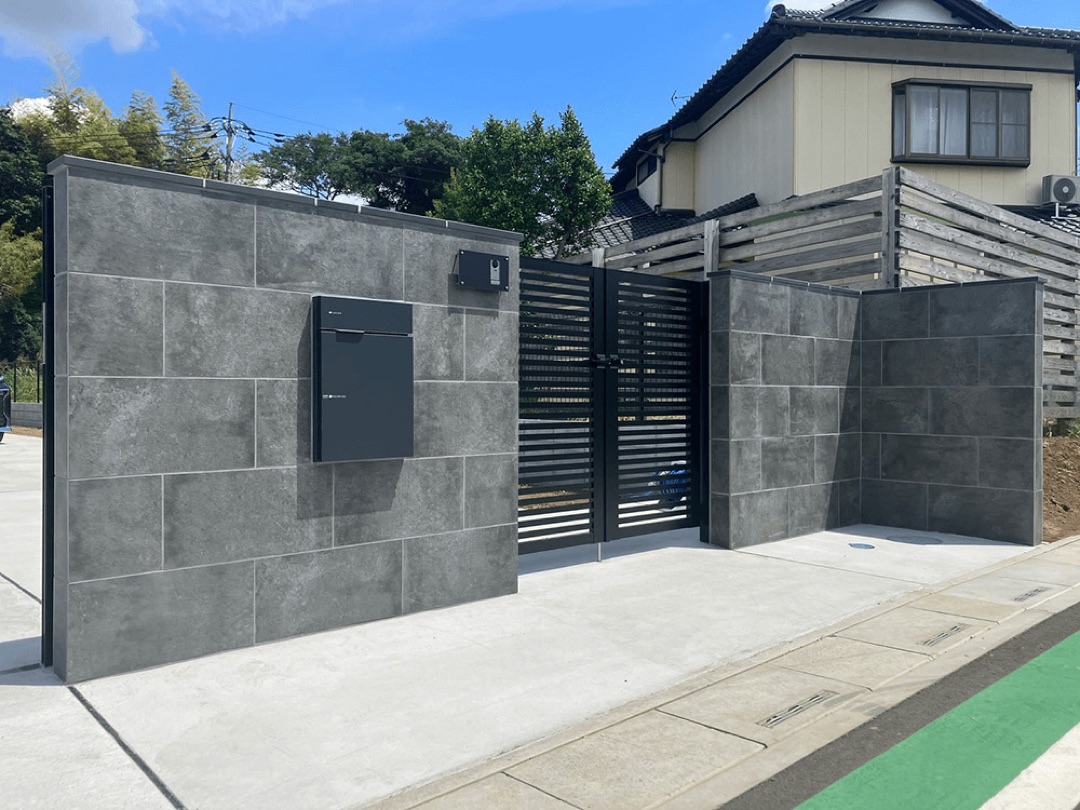 グレーのタイル張り門柱と黒い門扉のシンプルモダンな施工例