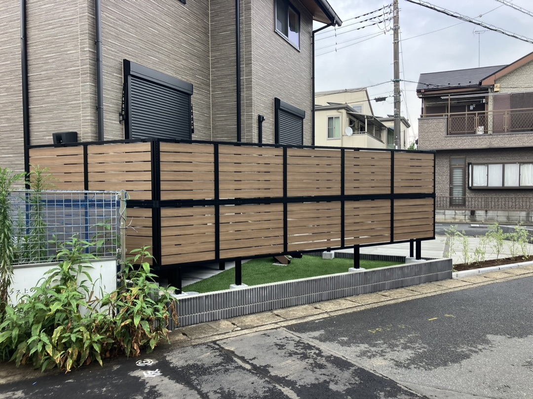芝生の上に木目調の目隠しフェンスを立てた施工例